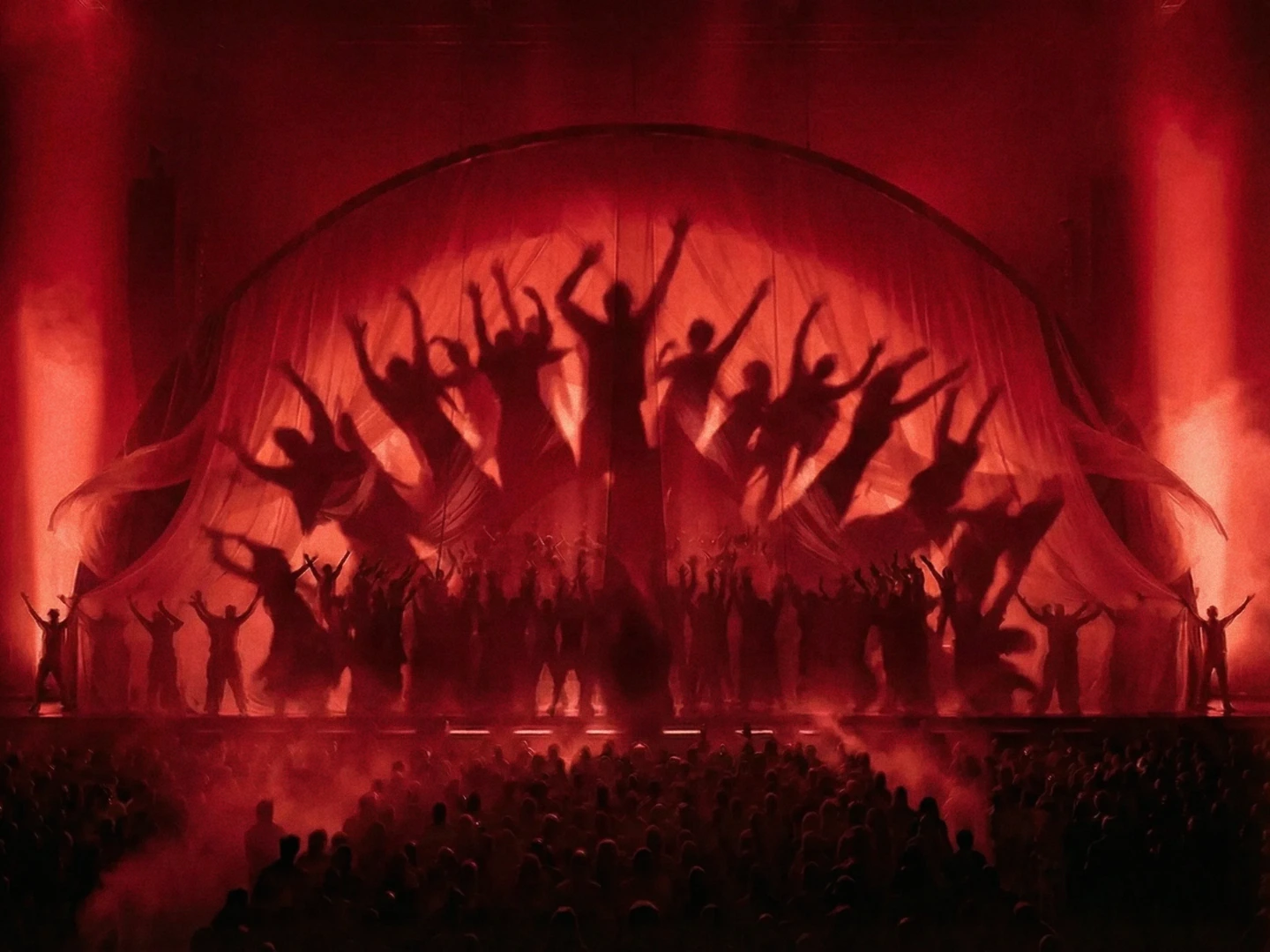 Dancers in silhouette behind a red curtain on stage